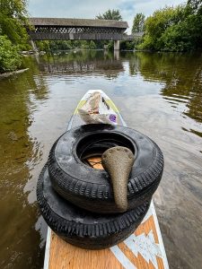 Tires and other debris retrieved from the Speed River stacked on top of a paddling board
