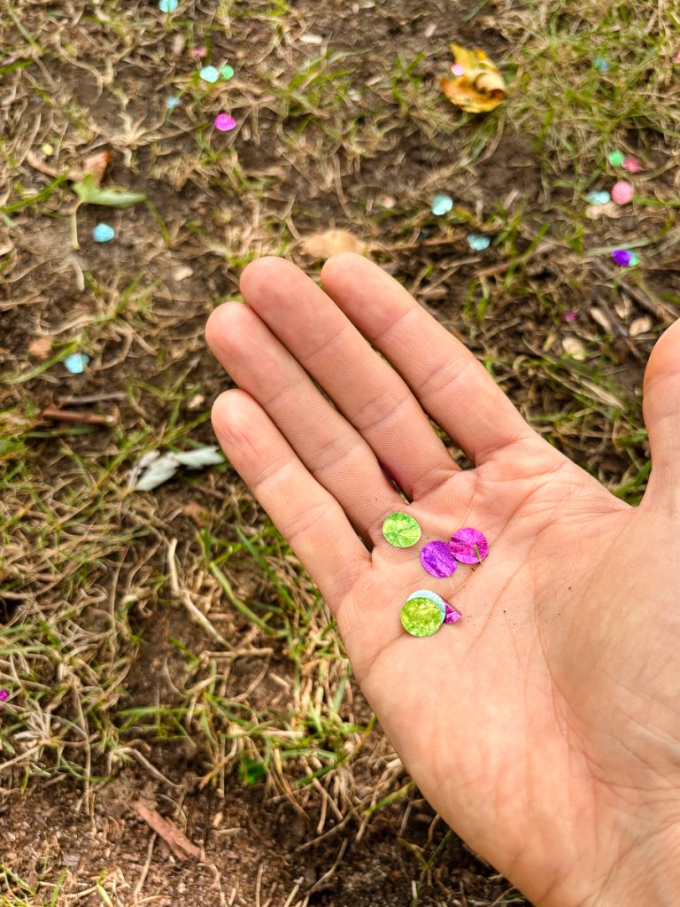 Hand holding confetti for removal from park grass